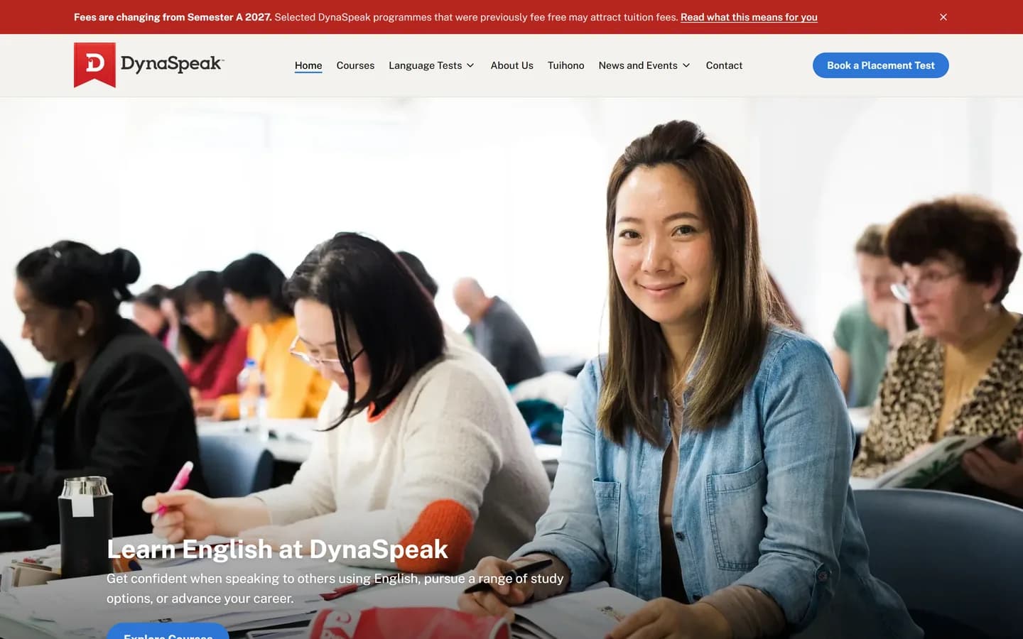 The DynaSpeak home page, showing a classroom photograph behind the heading "Learn English at DynaSpeak" and a placement test booking button.